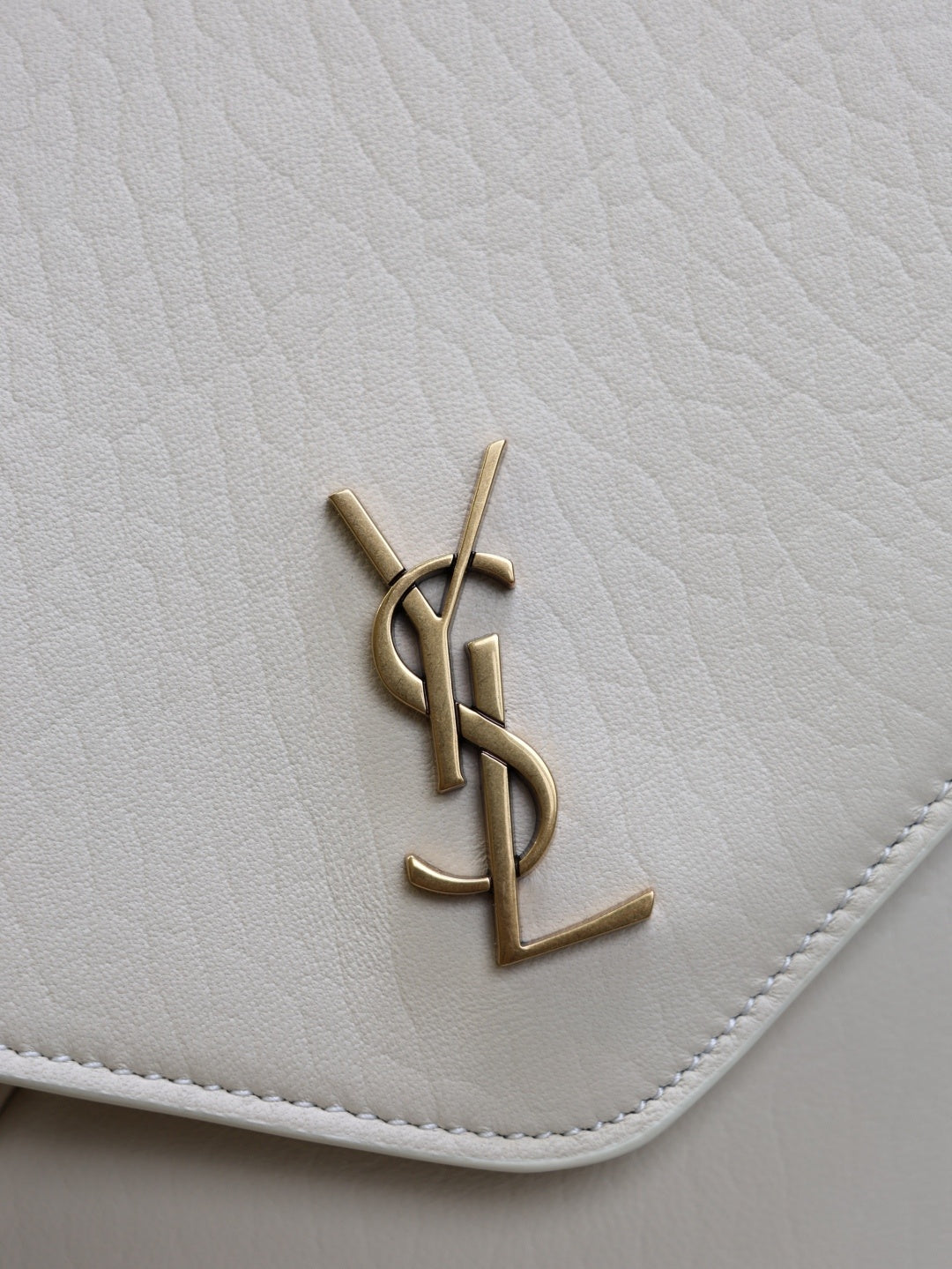 Saint Laurent Cassandra envelope bag gold YSL cassandre monogram hardware close-up on cream leather