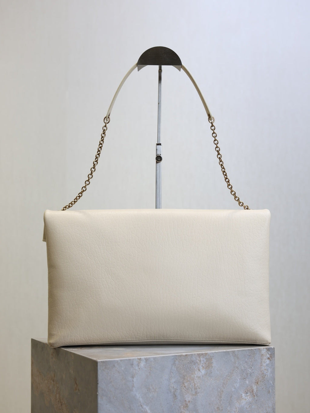 Saint Laurent Cassandra envelope bag back view with gold chain strap on stand