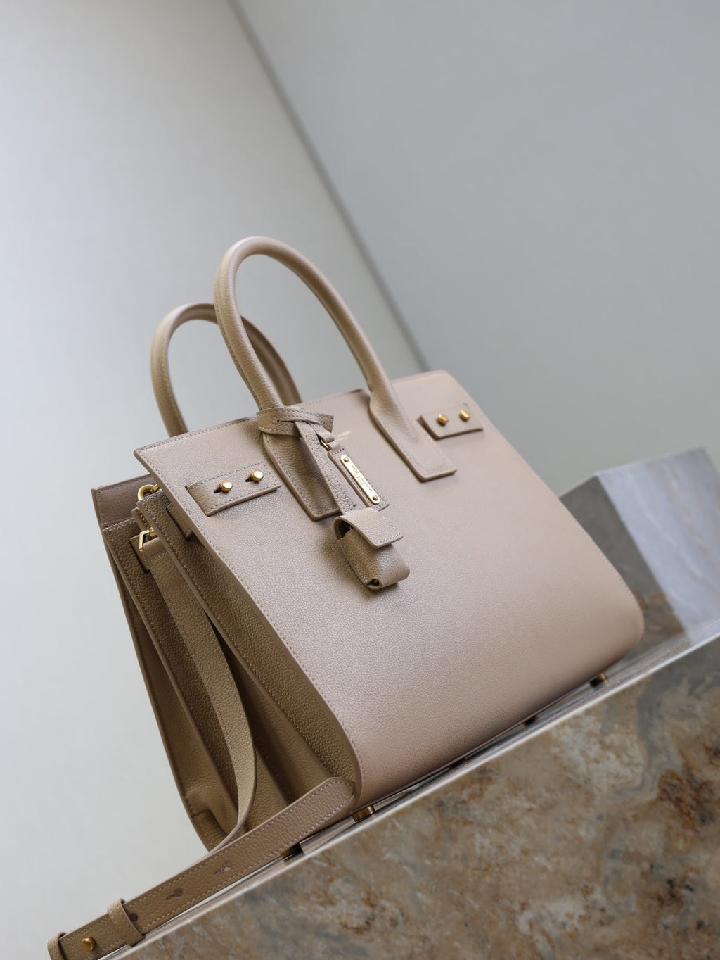 Saint Laurent Sac de Jour small bag three-quarter view showing stud hardware and logo charm