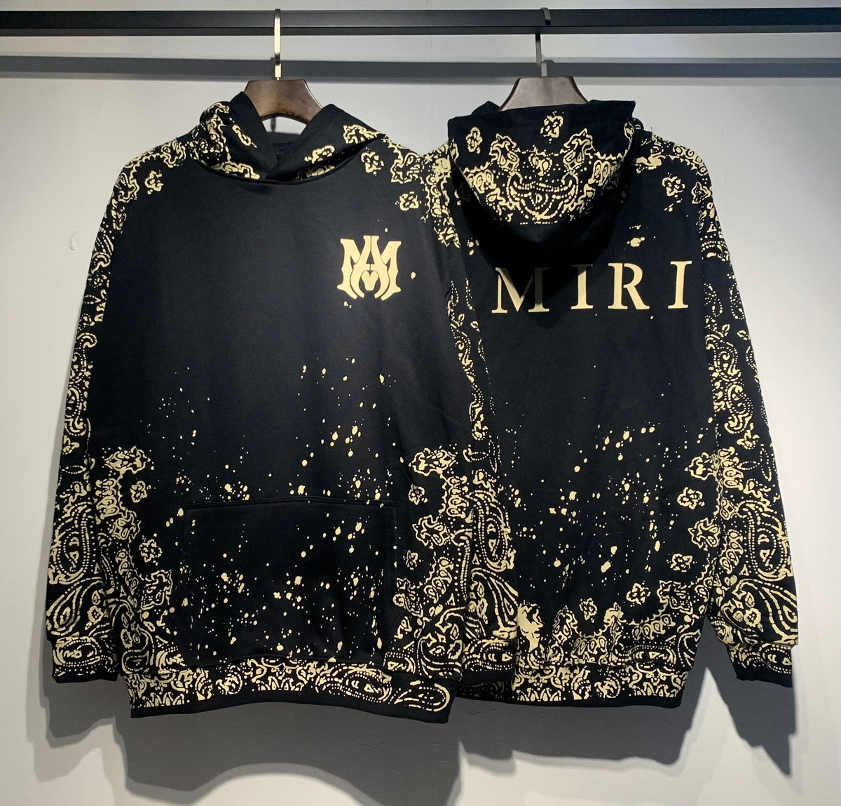 Amiri Paisley Bandana Hoodie – Black Gold front and back view on hangers side by side