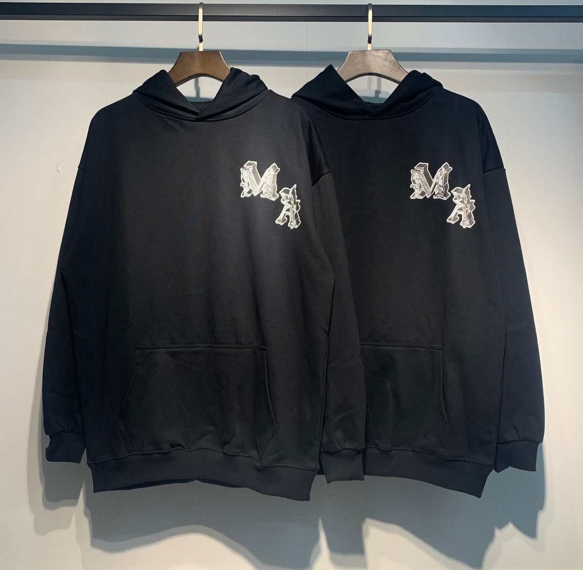 Amiri Angel Hoodie – Two Black hoodies front view showing MA monogram on chest