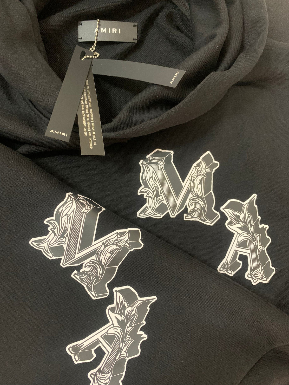 Amiri Angel Hoodie – MA monogram close-up with Amiri hang tag detail