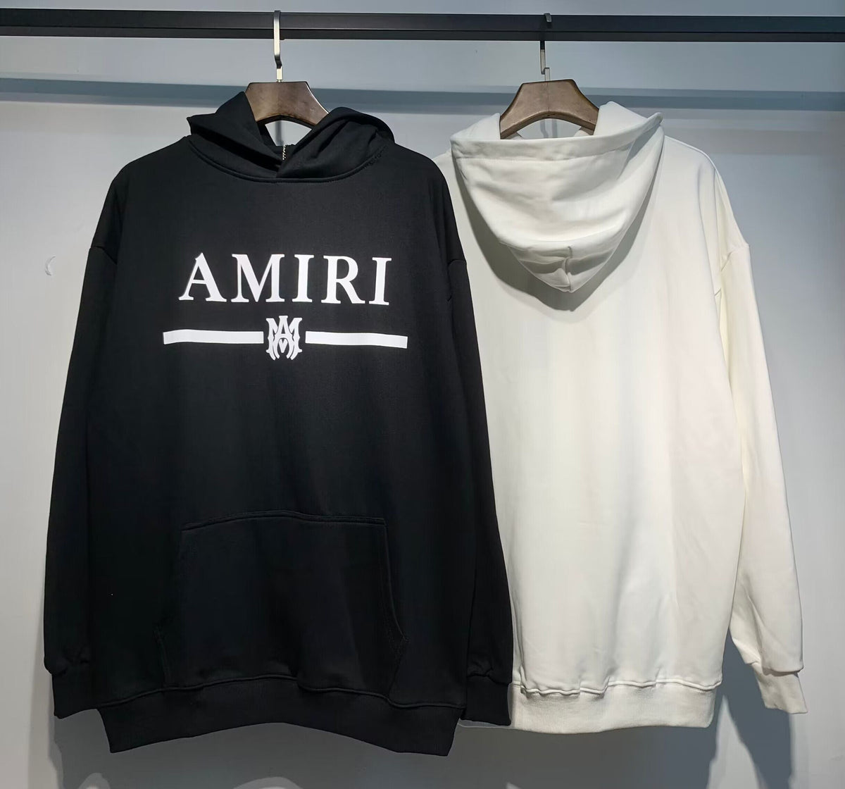 Amiri MA Bar Logo Hoodie – Black front and White back on hangers