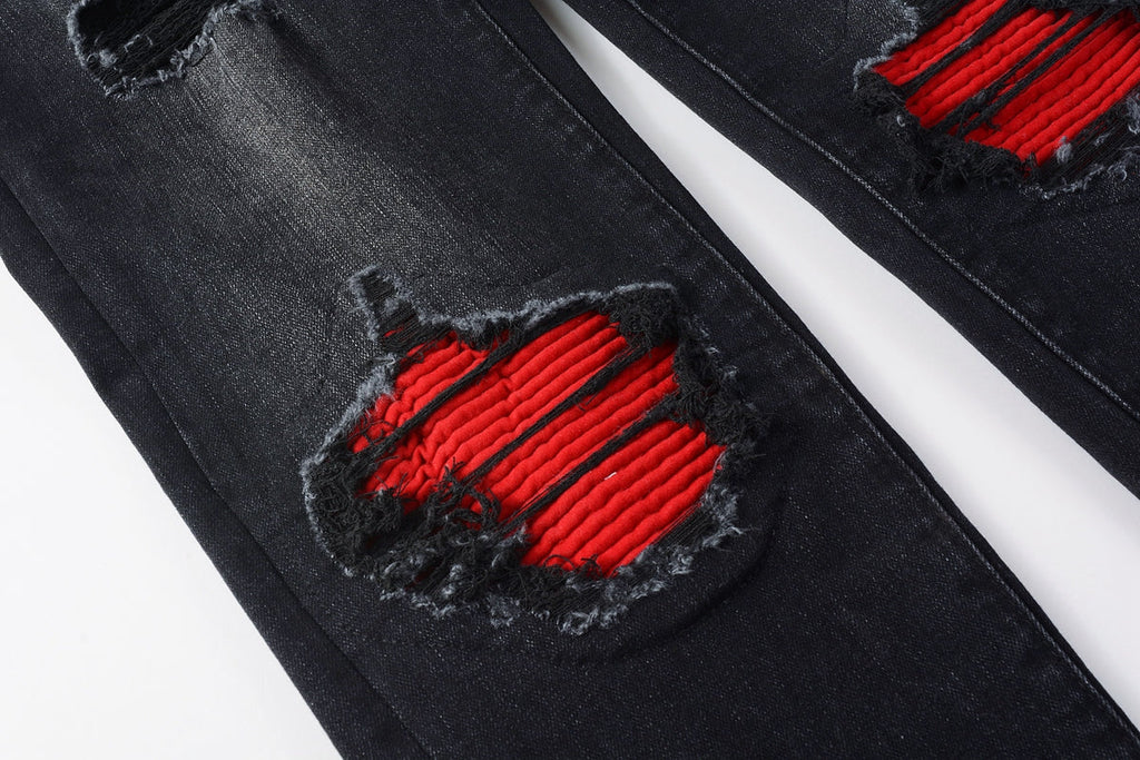 Full front view of AMIRI black distressed jeans with red patch inserts