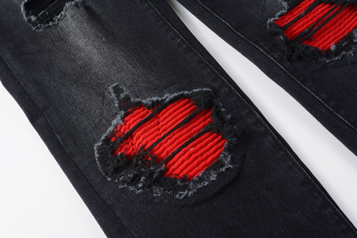 Full front view of AMIRI black distressed jeans with red patch inserts